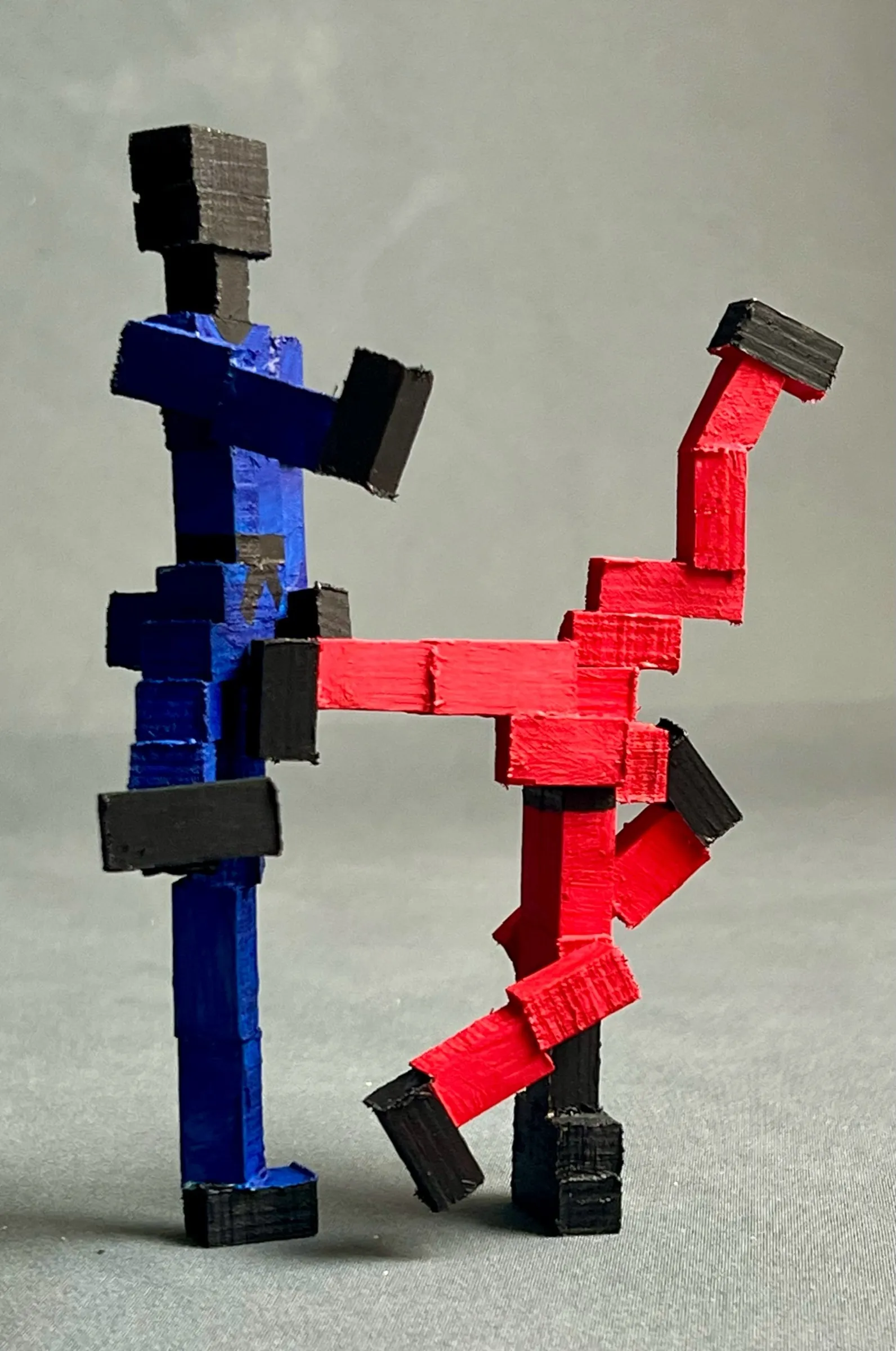 The finished piece: a blue block figure stands upright on one leg while a red block figure is swung around it, legs in the air.
