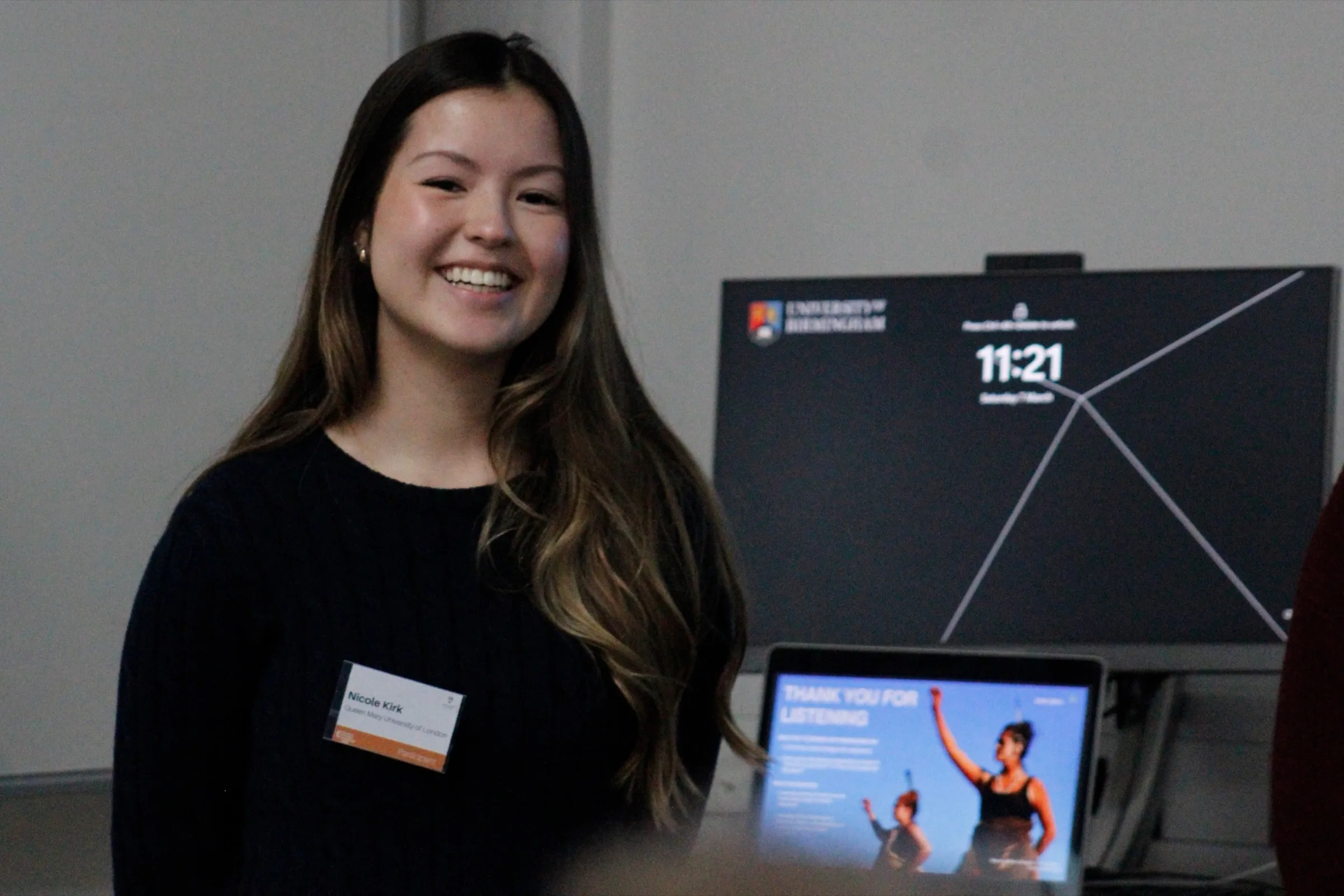 Me smiling beside a screen at the Design Challenge.