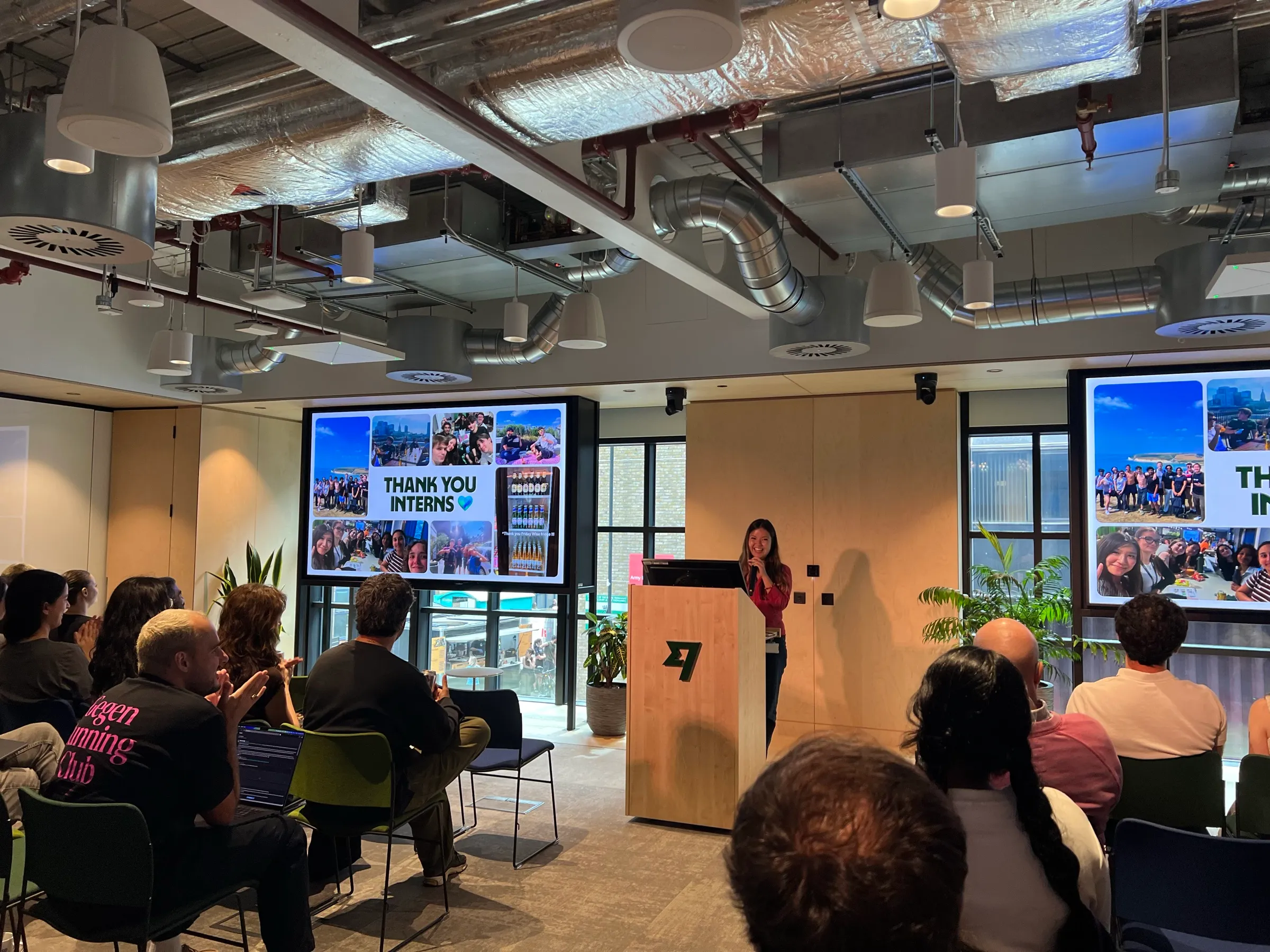 Me speaking at the Wise podium, a Thank You Interns slide on the screens and the audience applauding.