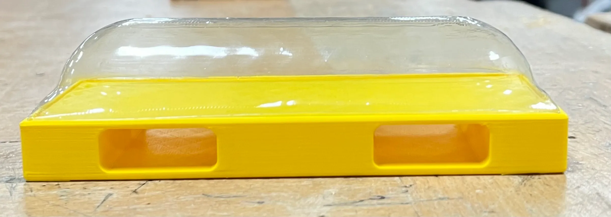 The yellow housing with a clear vacuum-formed cover over the top.