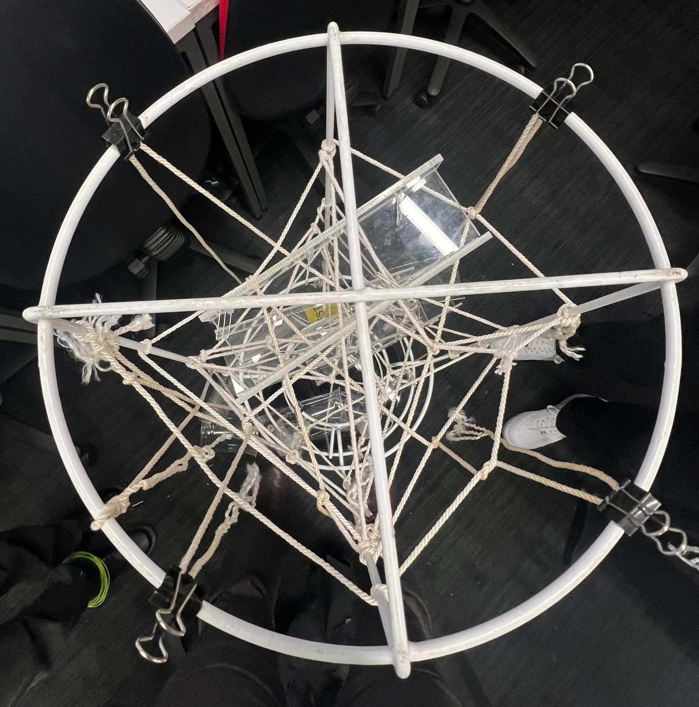 Looking down into the tower: rope knotted across a white ring like a web, holding clear acrylic ramps.