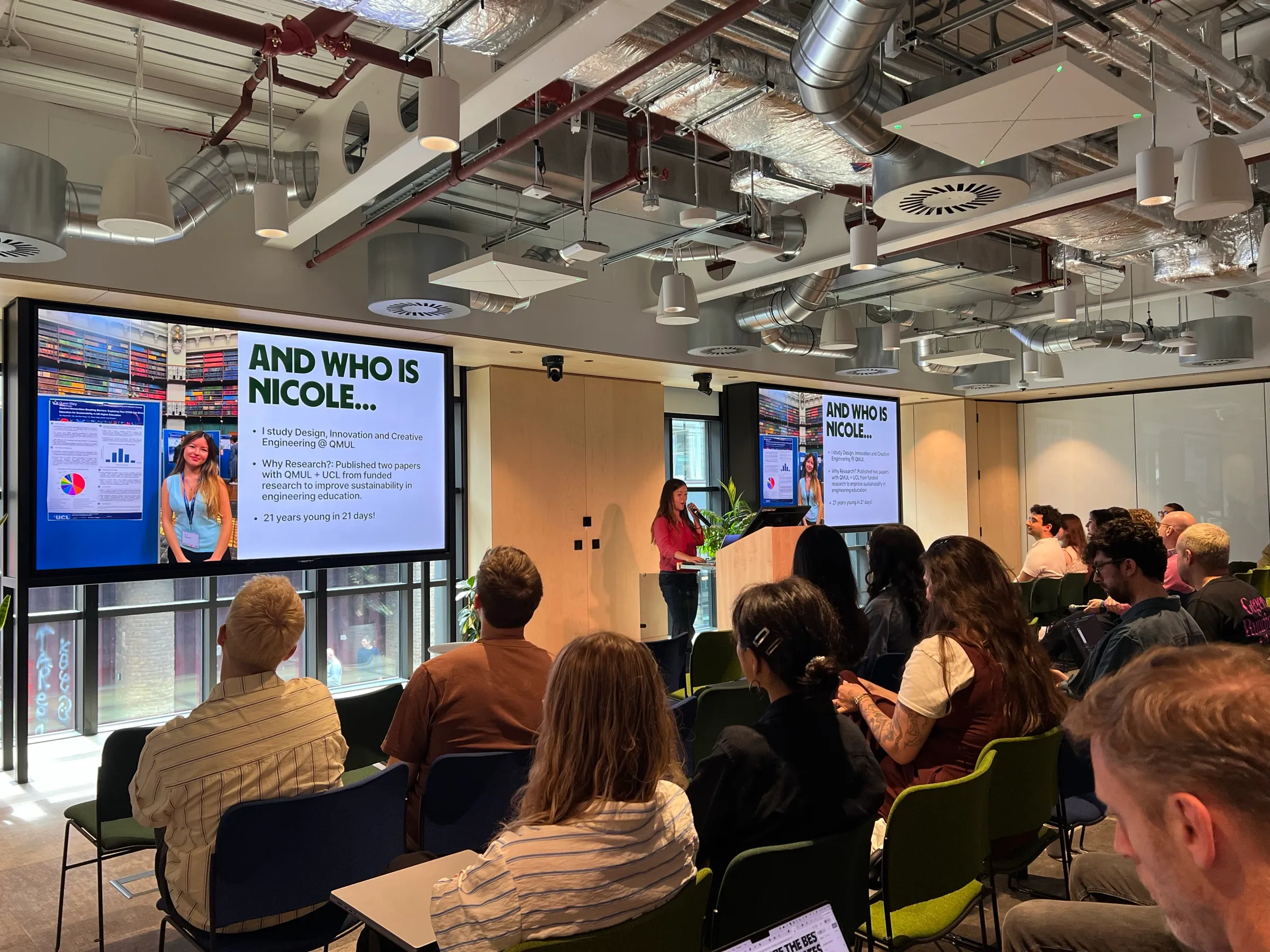 Me at a lectern in the Wise office, introducing myself to a seated audience, with my slide on the screens behind.