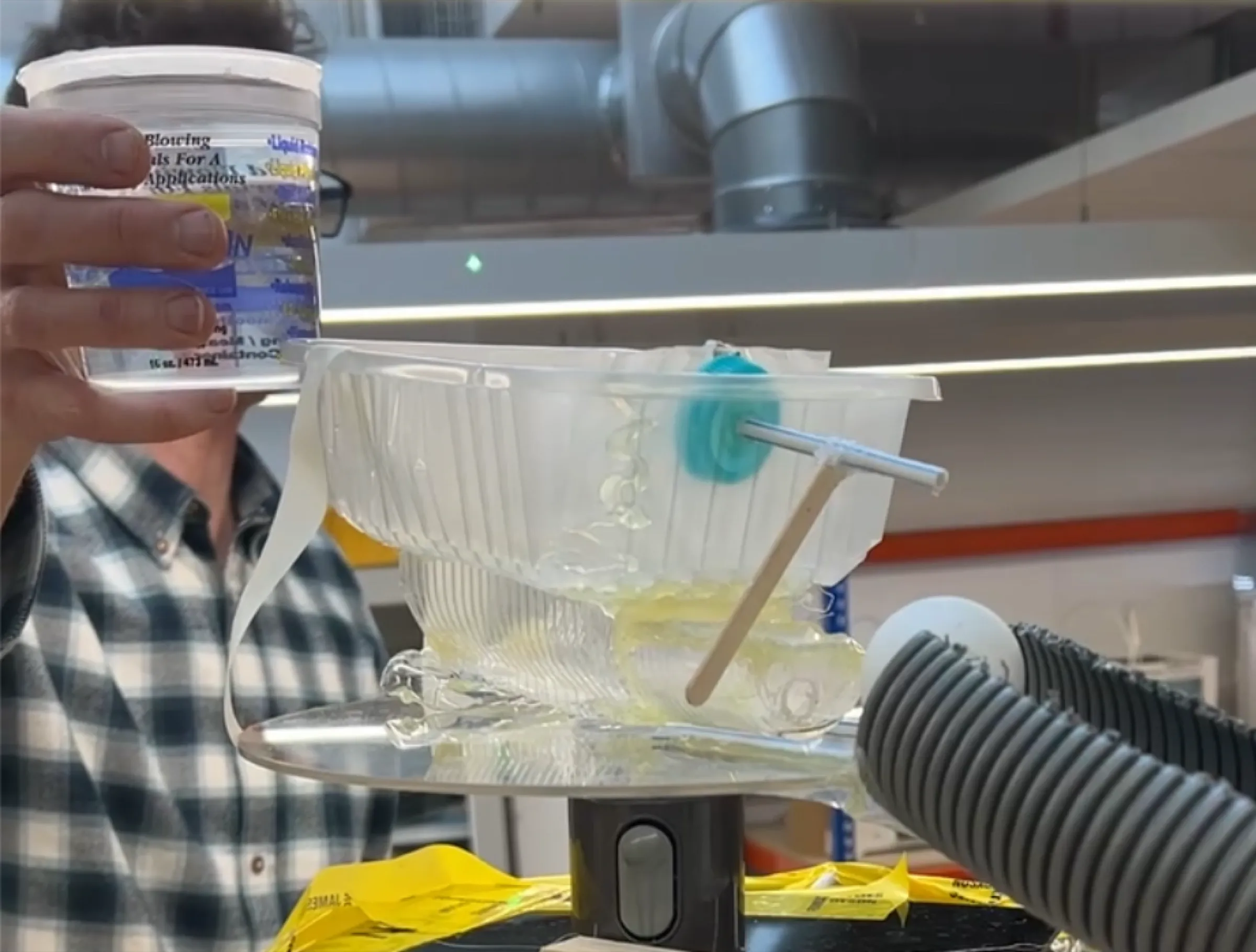 Water being poured from a tub into a clear test rig on a stand.