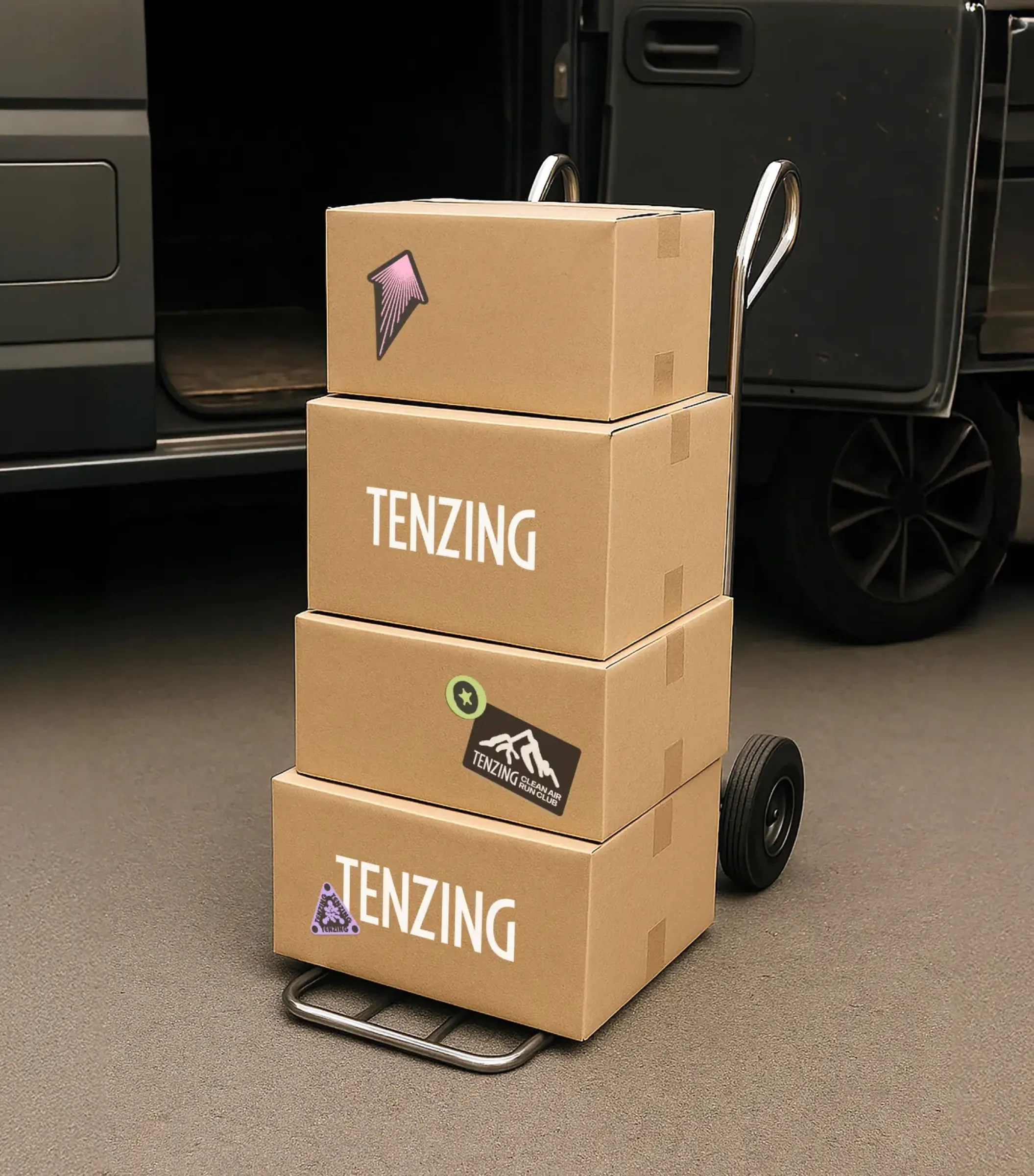 Tenzing boxes on a hand truck by a delivery van.